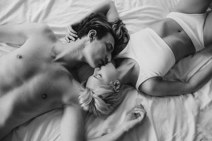 Szerelmes pár csókolózva fekszik az ágyon